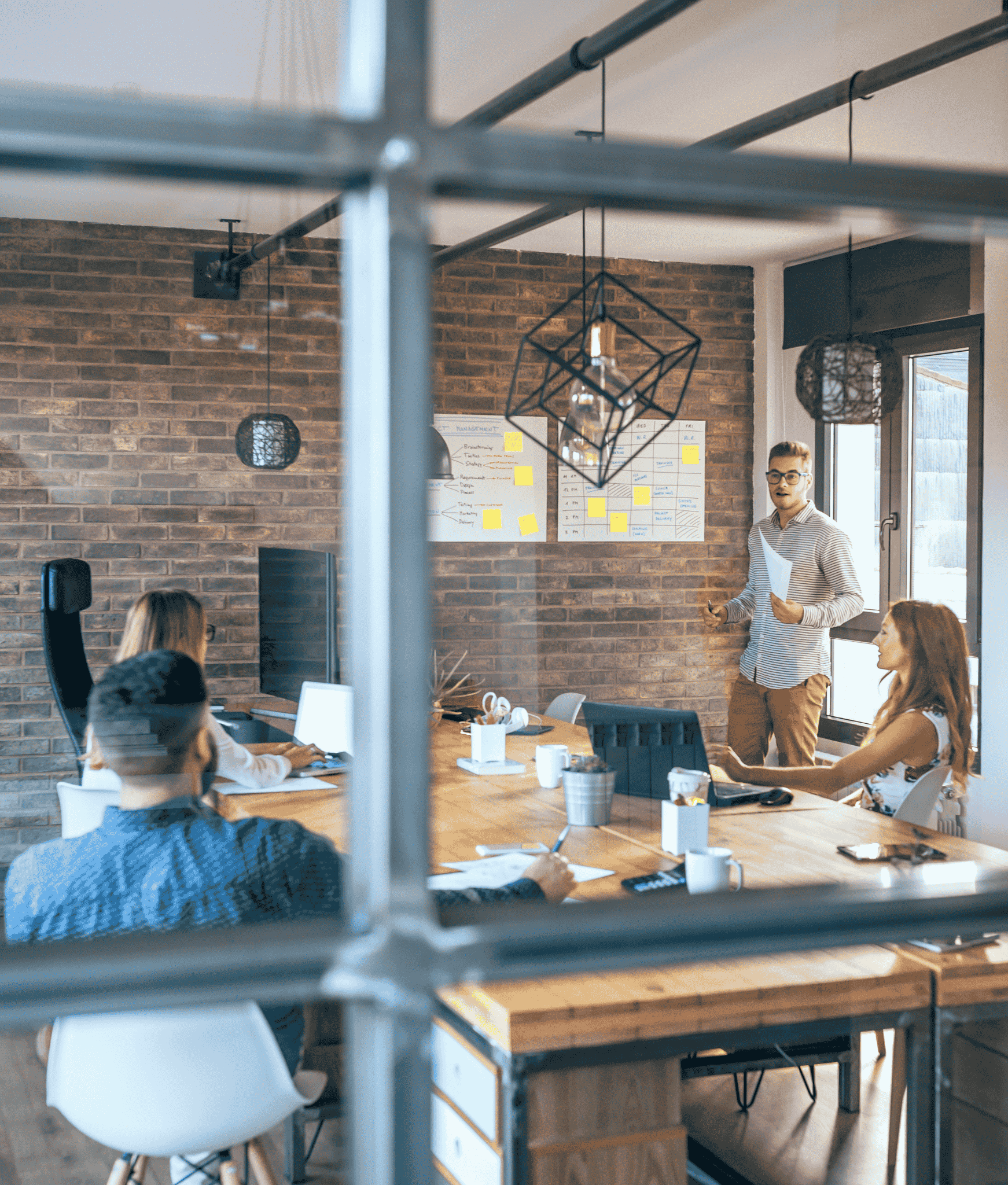 A picture taken outside of a meeting room as a team engages in a discussion.